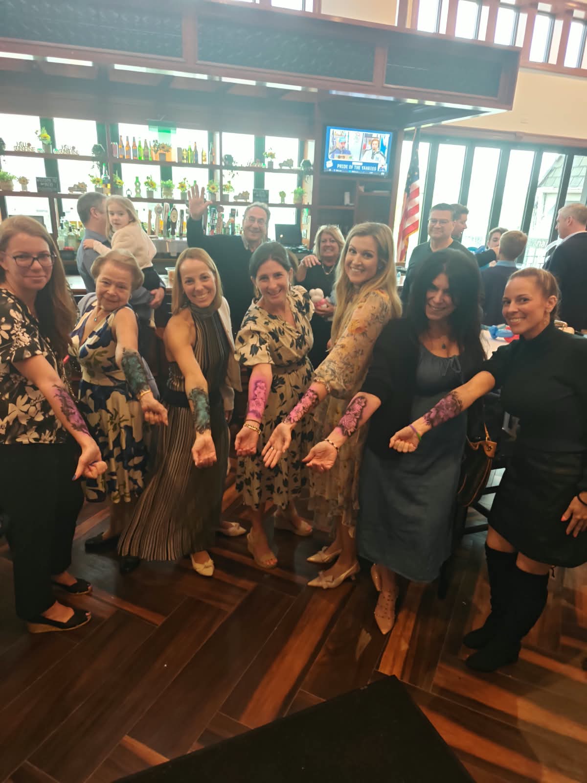 A group of guests lined up showing off matching airbrushed floral forearm tattoos at a party