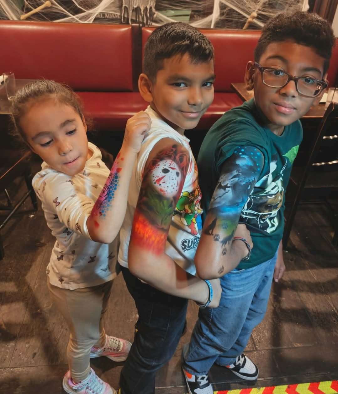 Three kids showing off airbrushed sleeves at a Halloween party