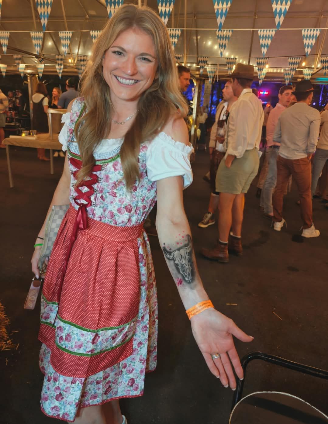 A guest in a dirndl showing an airbrushed bull skull on her forearm