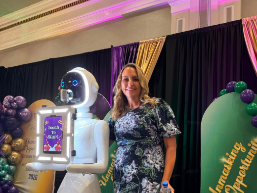 Guest posing beside the roaming robot photo booth at a corporate gala