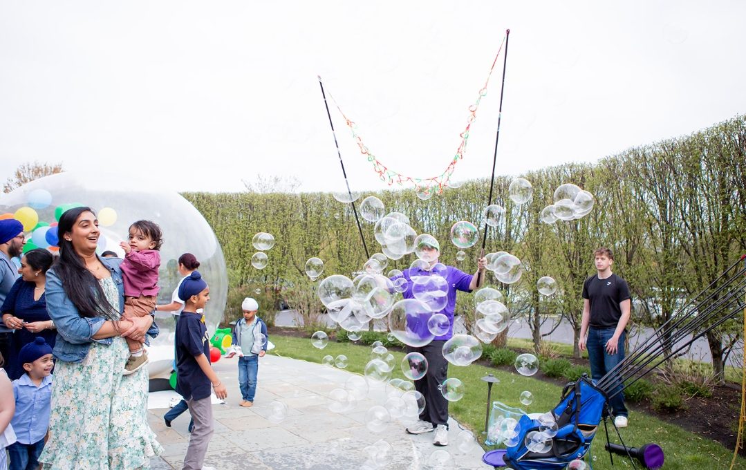 Scotty sending a wall of giant bubbles over kids at an outdoor party