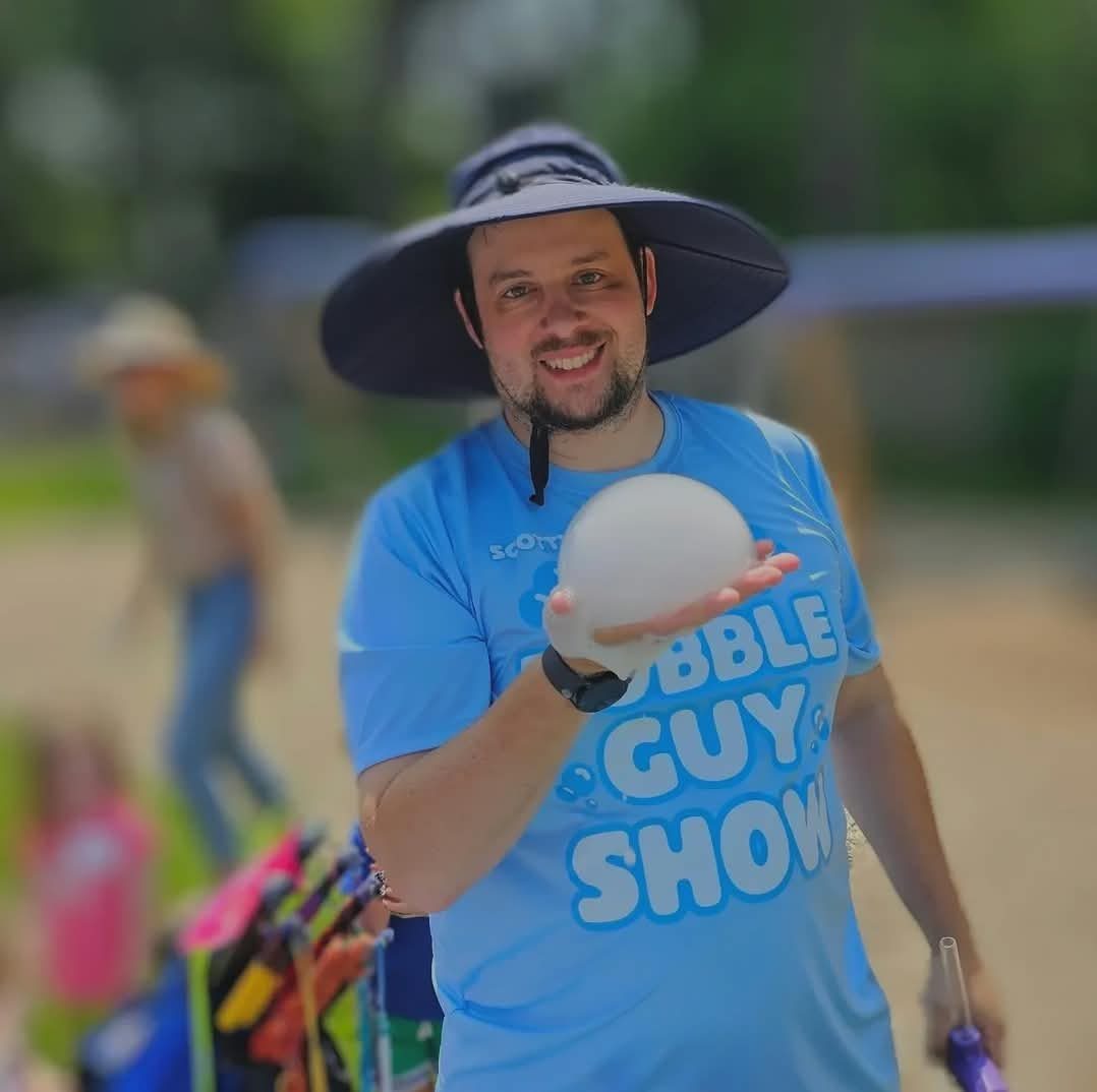 Scotty Kazan of My Balloon Guy holding a smoke-filled bubble at an outdoor show