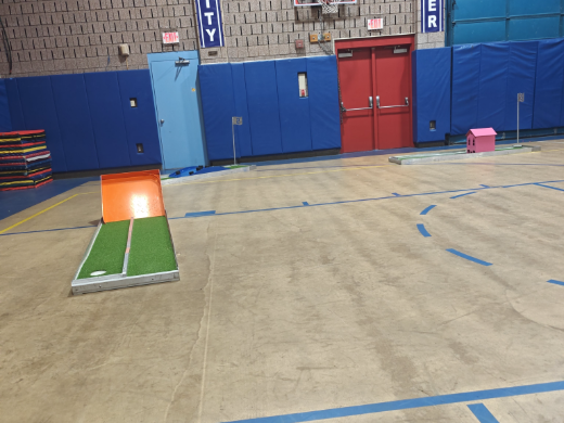 Mini golf holes laid out down the length of a school gym for an indoor event