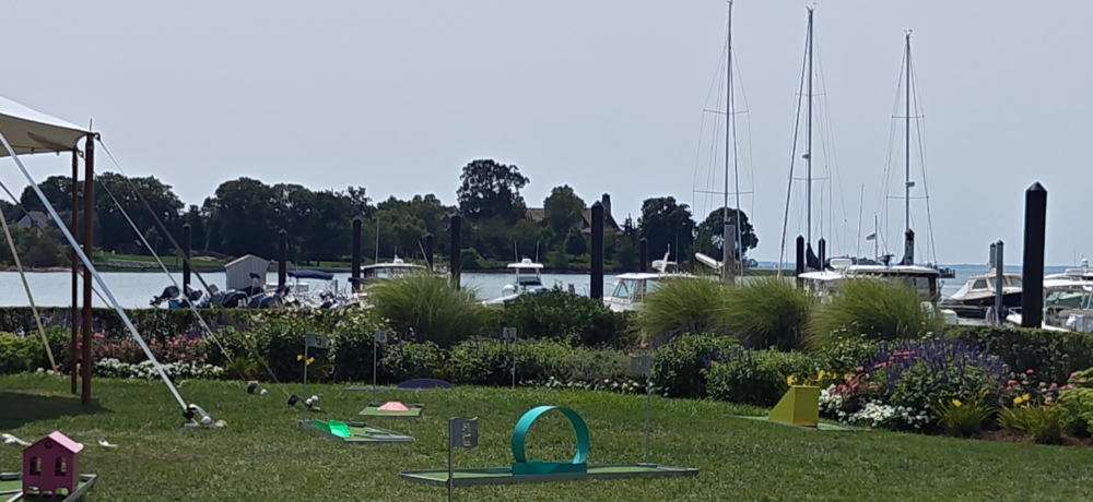 Portable mini golf holes set up across a waterfront lawn in Fairfield County