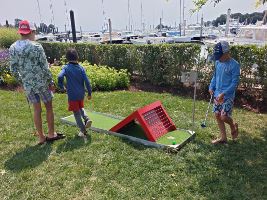 Boys putting through the red ramp obstacle hole on a marina lawn