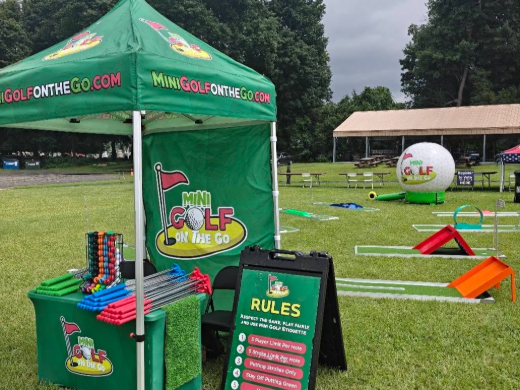 Branded Mini Golf on the Go tent with putters, scorecards and the rules board at an outdoor event