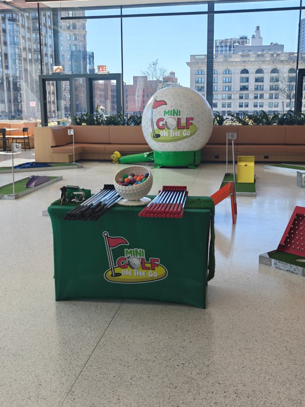 Mini golf holes set up in a Manhattan office lobby with a giant inflatable golf ball