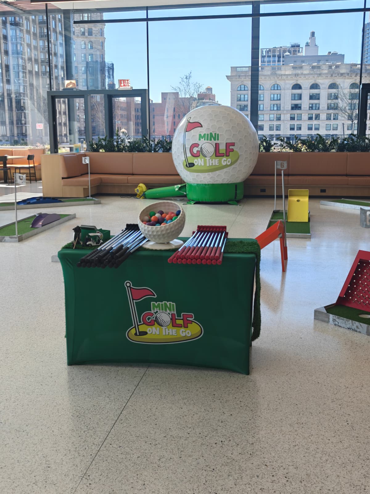 Mini golf course laid out in a glass-walled city loft with a giant inflatable golf ball