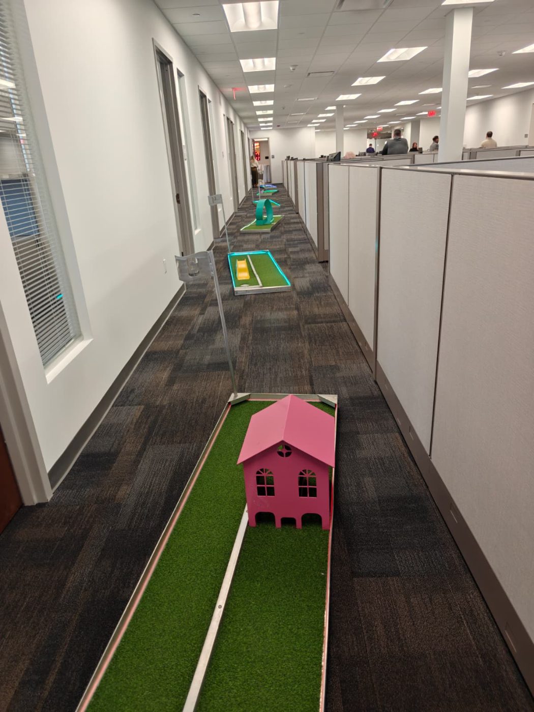 Mini golf holes running down an office corridor between cubicles