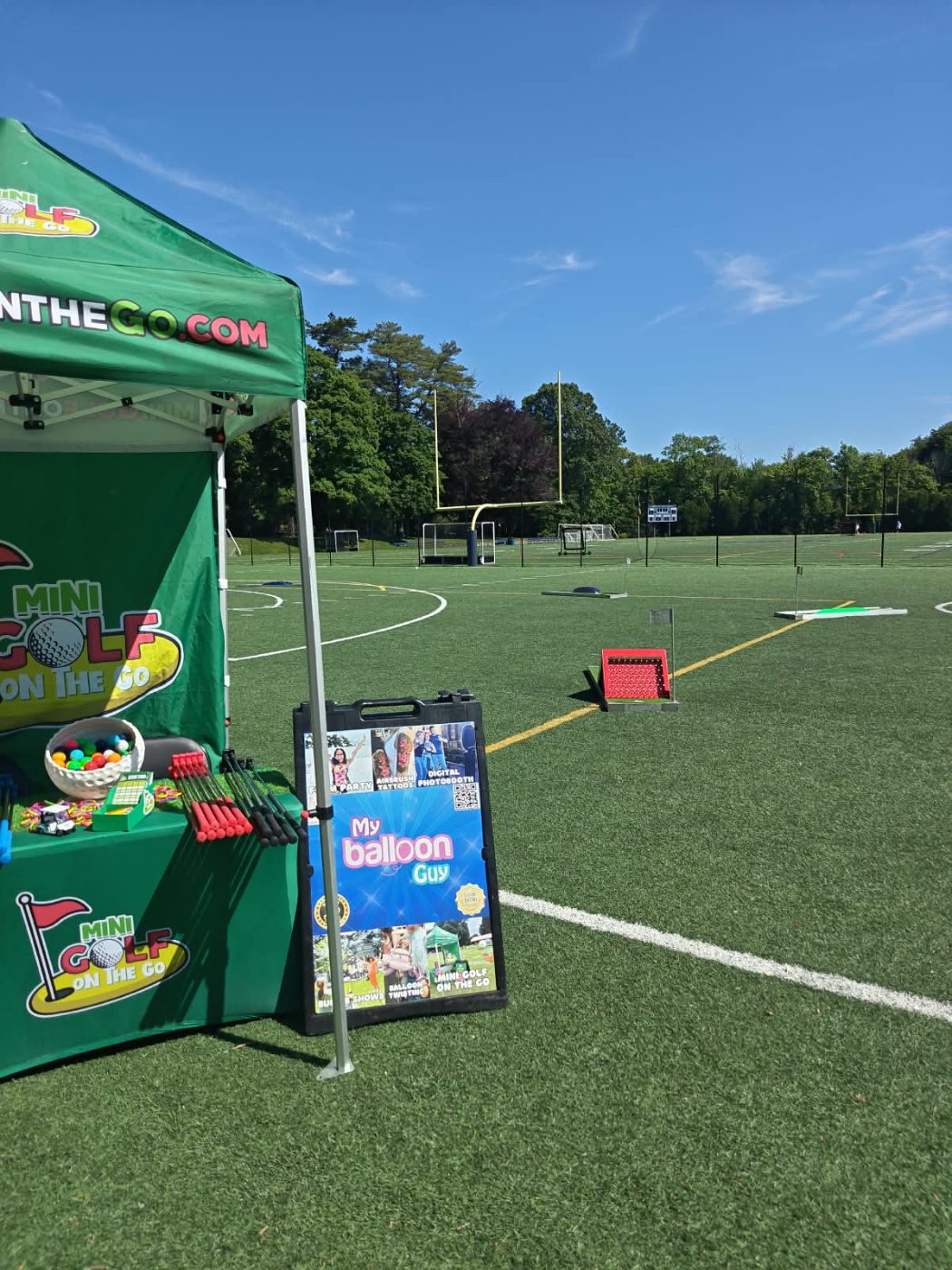 Mini golf on the Go tent and My Balloon Guy sign on a turf athletic field