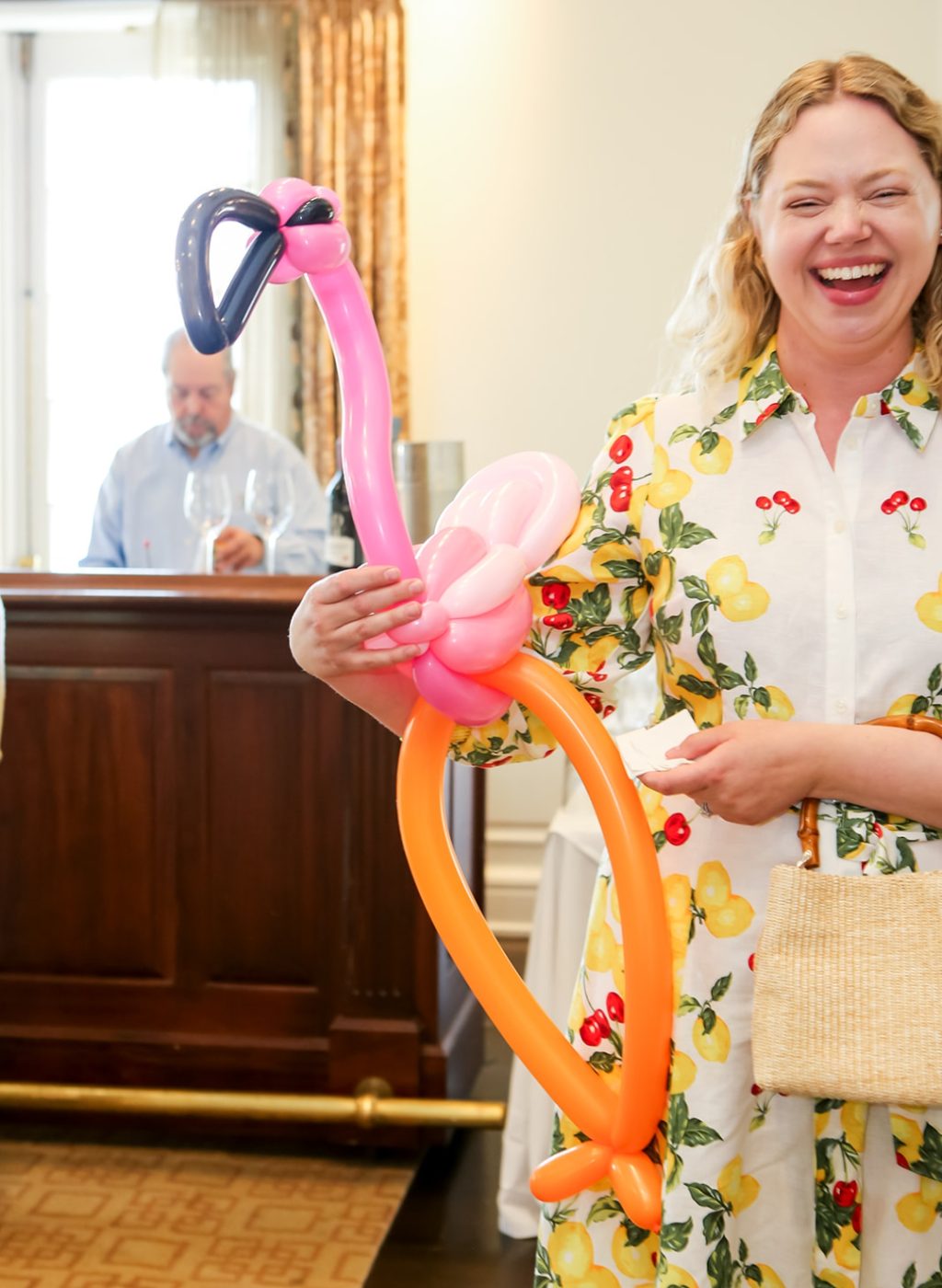 A guest laughing with a life-size balloon flamingo wearing sunglasses