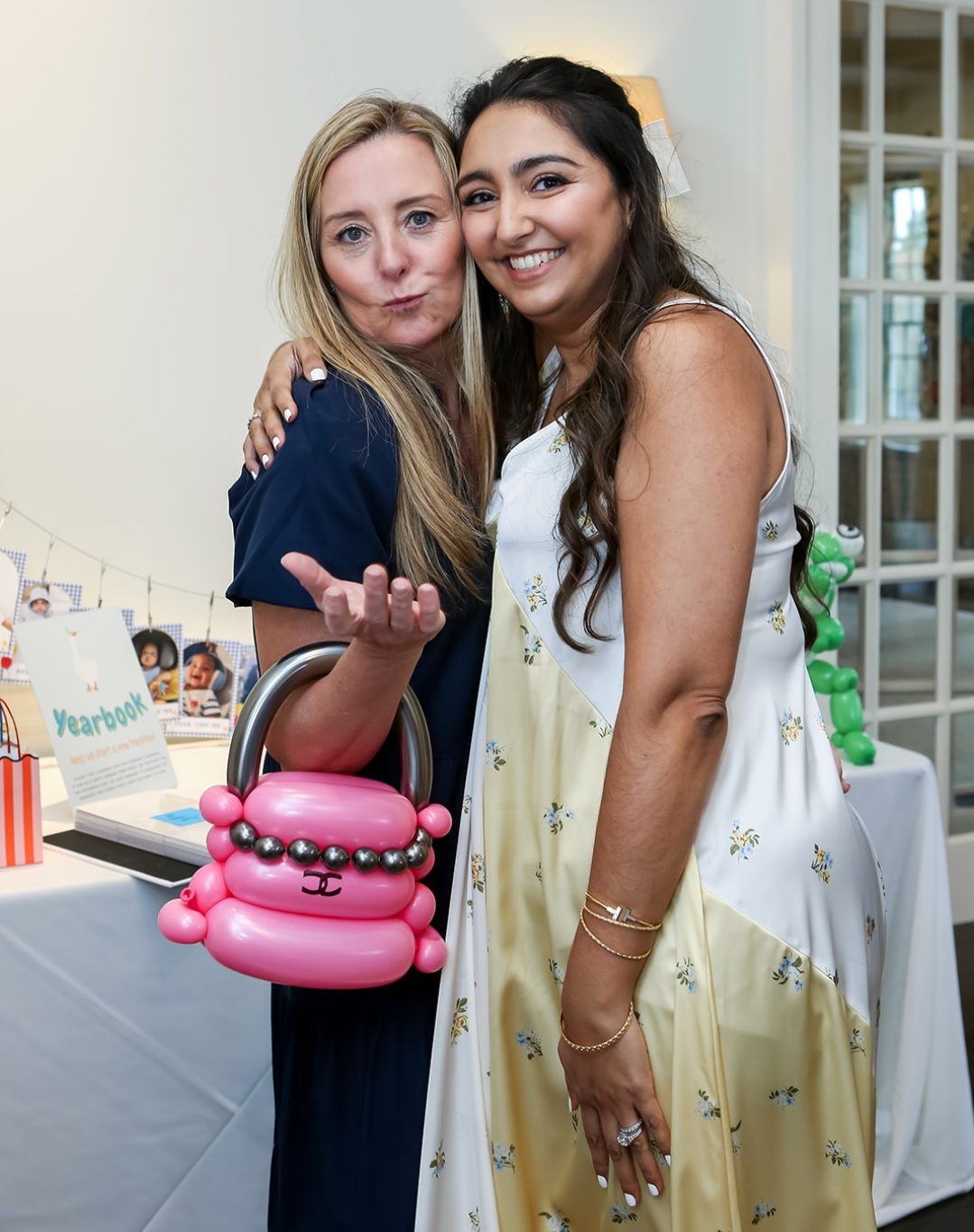 Two guests posing with a pink designer balloon handbag with a silver bead chain